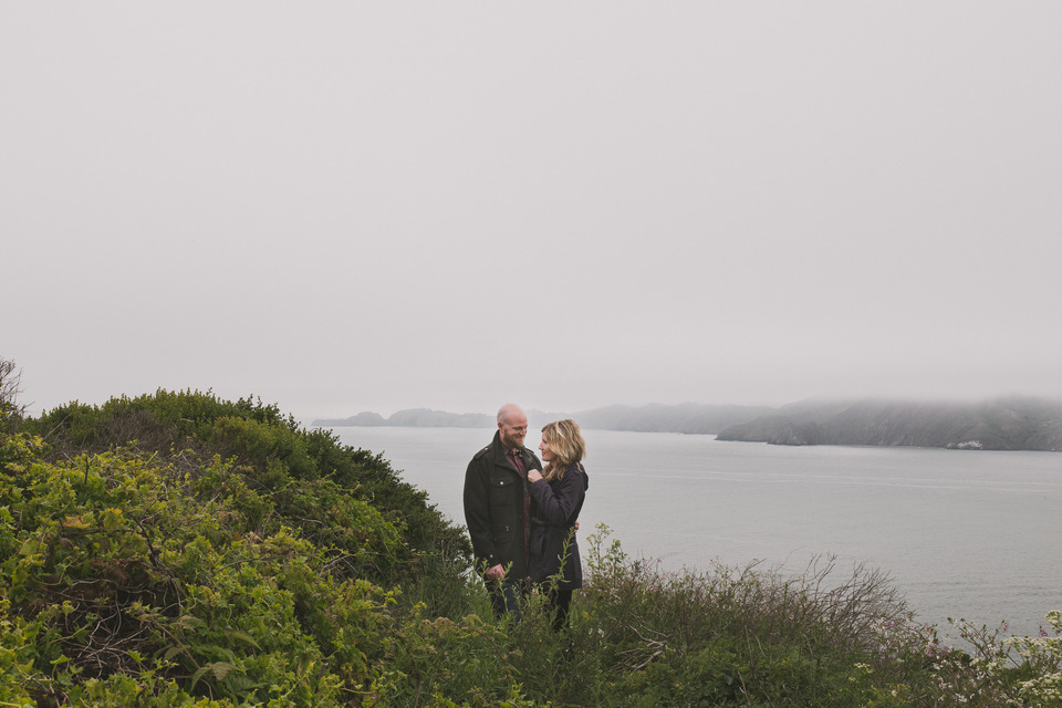 couple standing on a cliff overlooking the ocean